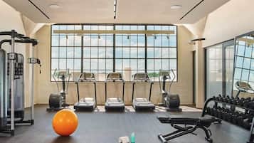 Un gimnasio con cintas de correr, elípticas y pesas libres.
