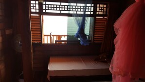 A room with a bed, a window with wooden shutters, and a fan. - Dyke rest (Trincomalee)
