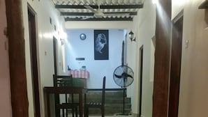A hallway with a tiled floor leading to a staircase. There is a table with a red and white checkered tablecloth and a chair in the background. - Dyke rest (Trincomalee)