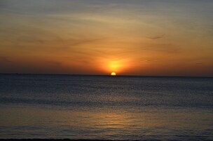 Un atardecer sobre un mar tranquilo con un horizonte despejado.
