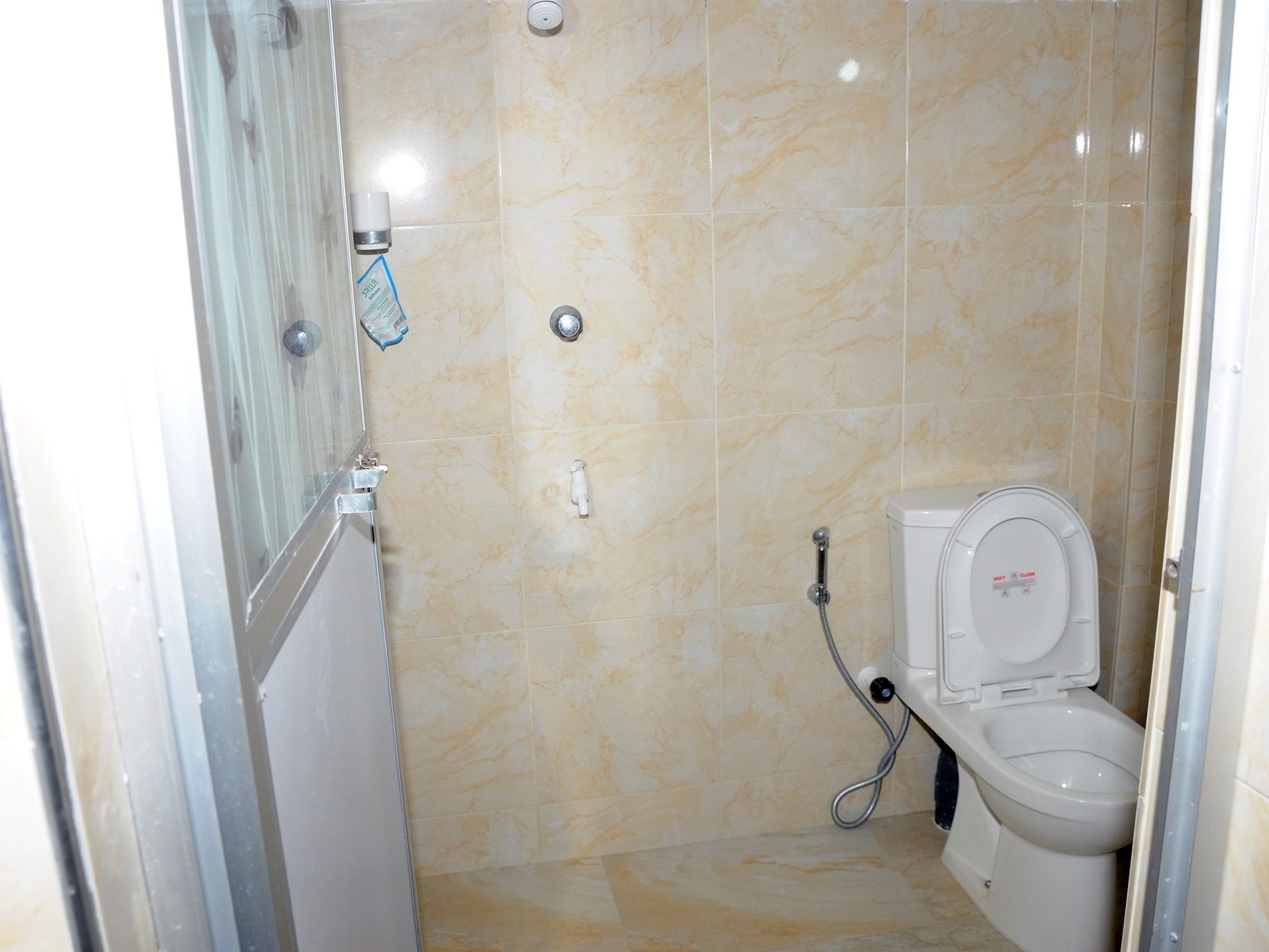 A small, tiled bathroom with a shower, toilet, and a glass shower enclosure.