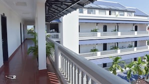 Un hôtel à plusieurs étages doté d’un balcon couvert, de murs extérieurs blancs et de toits recouverts de tuiles bleues.