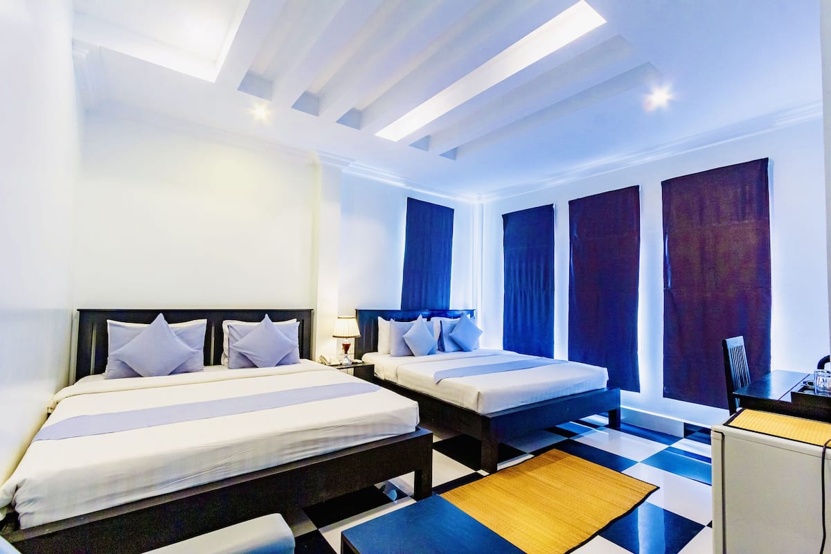 A hotel room with two beds, a desk, and a chair.