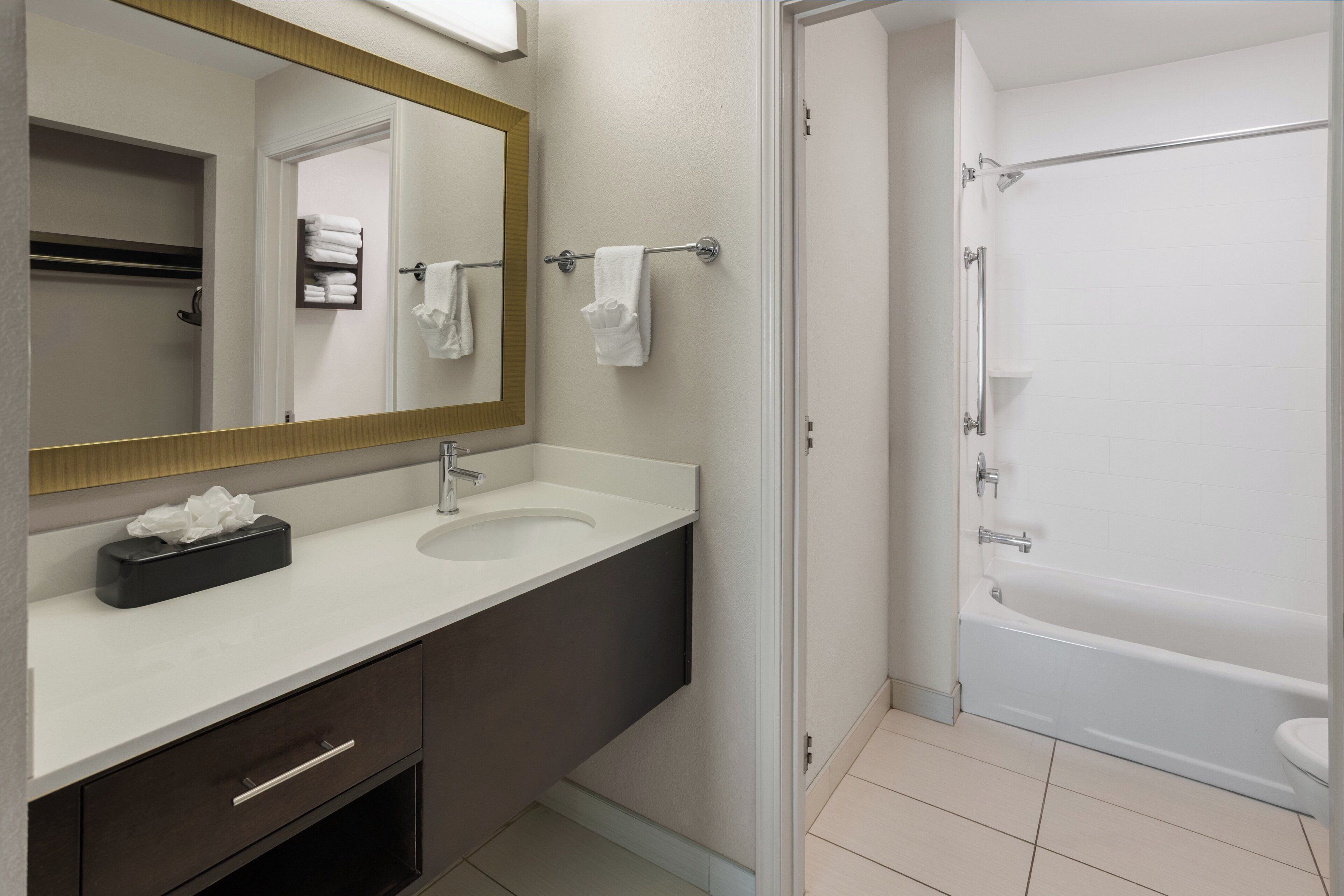 A bathroom with a double sink, a mirror, a towel rack, a toilet, and a bathtub.