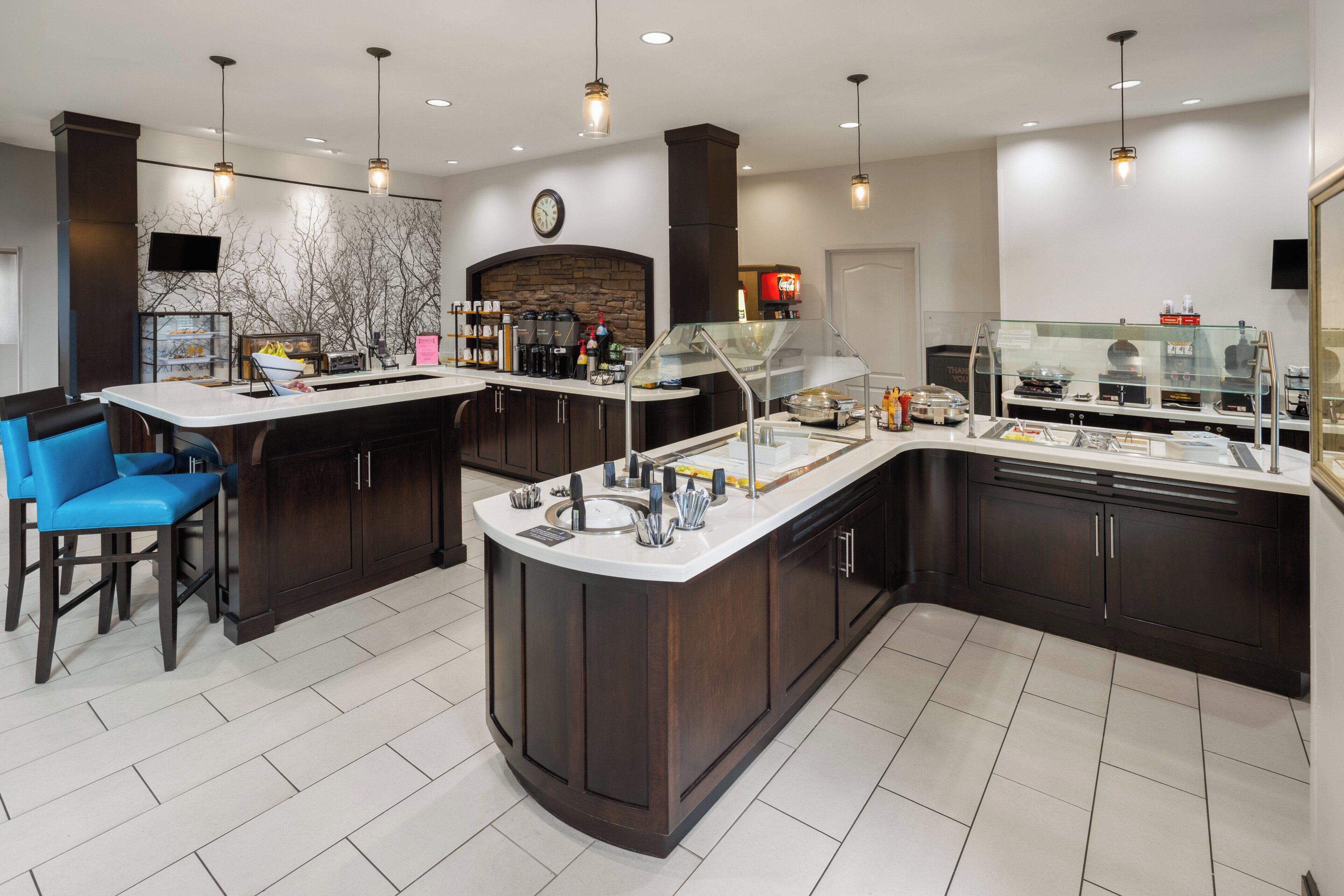 A modern kitchen with a central island, bar seating, and a stone backsplash.