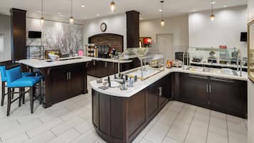 A modern kitchen with a central island, bar seating, and a stone backsplash.
