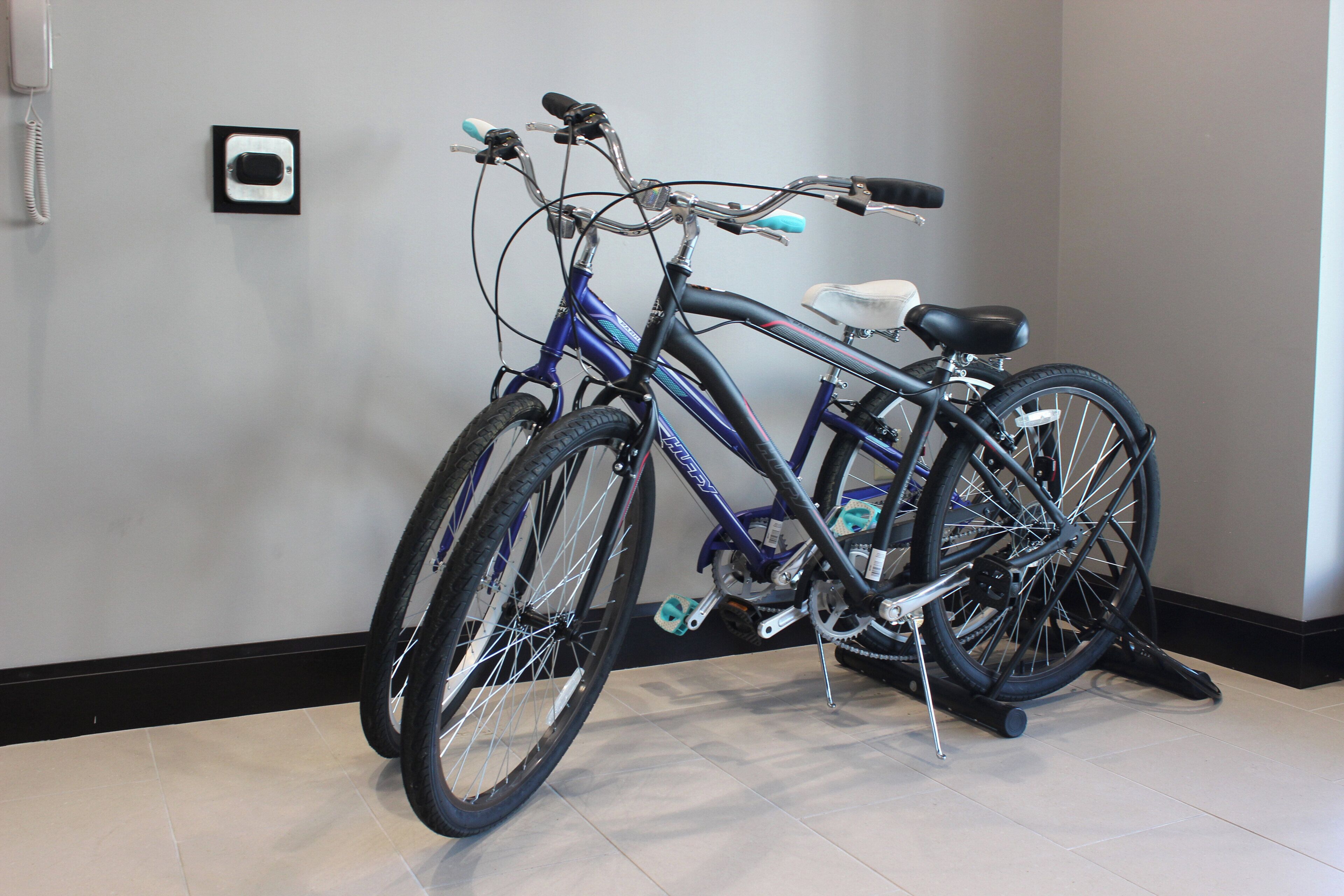 A bicycle parked indoors with a tiled floor and a plain wall in the background.