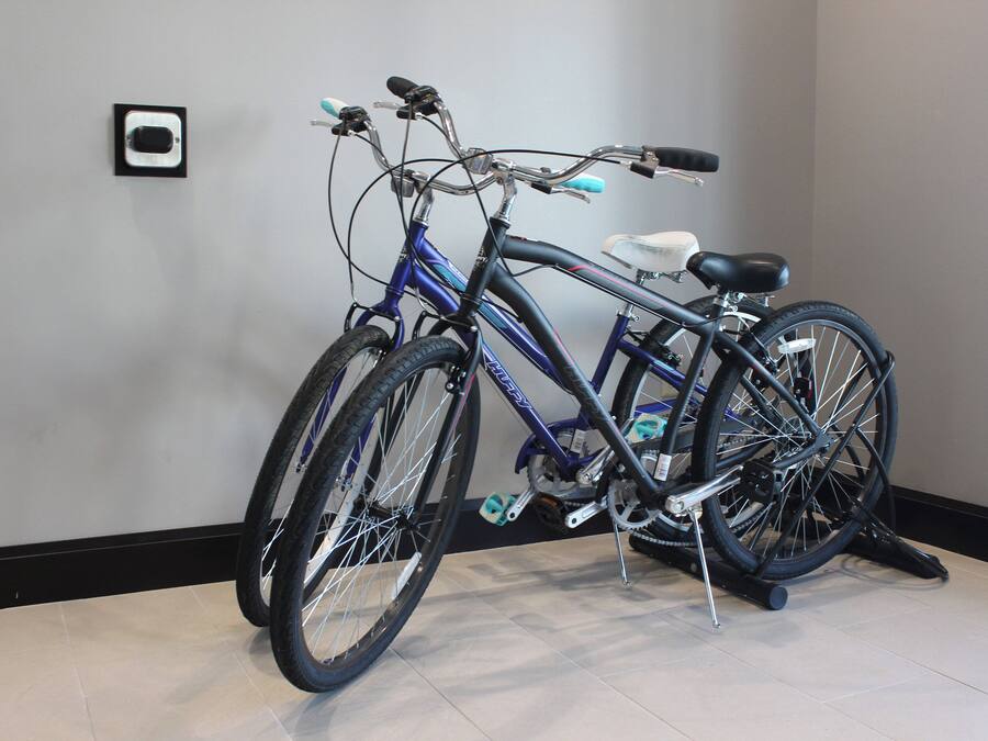 A bicycle parked indoors with a tiled floor and a plain wall in the background.