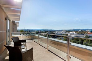 A balcony with wicker furniture and a clear view of the cityscape. - TownePlace Suites San Mateo Foster City (Foster City)