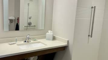 Un baño con lavamanos blanco, espejo y ducha.