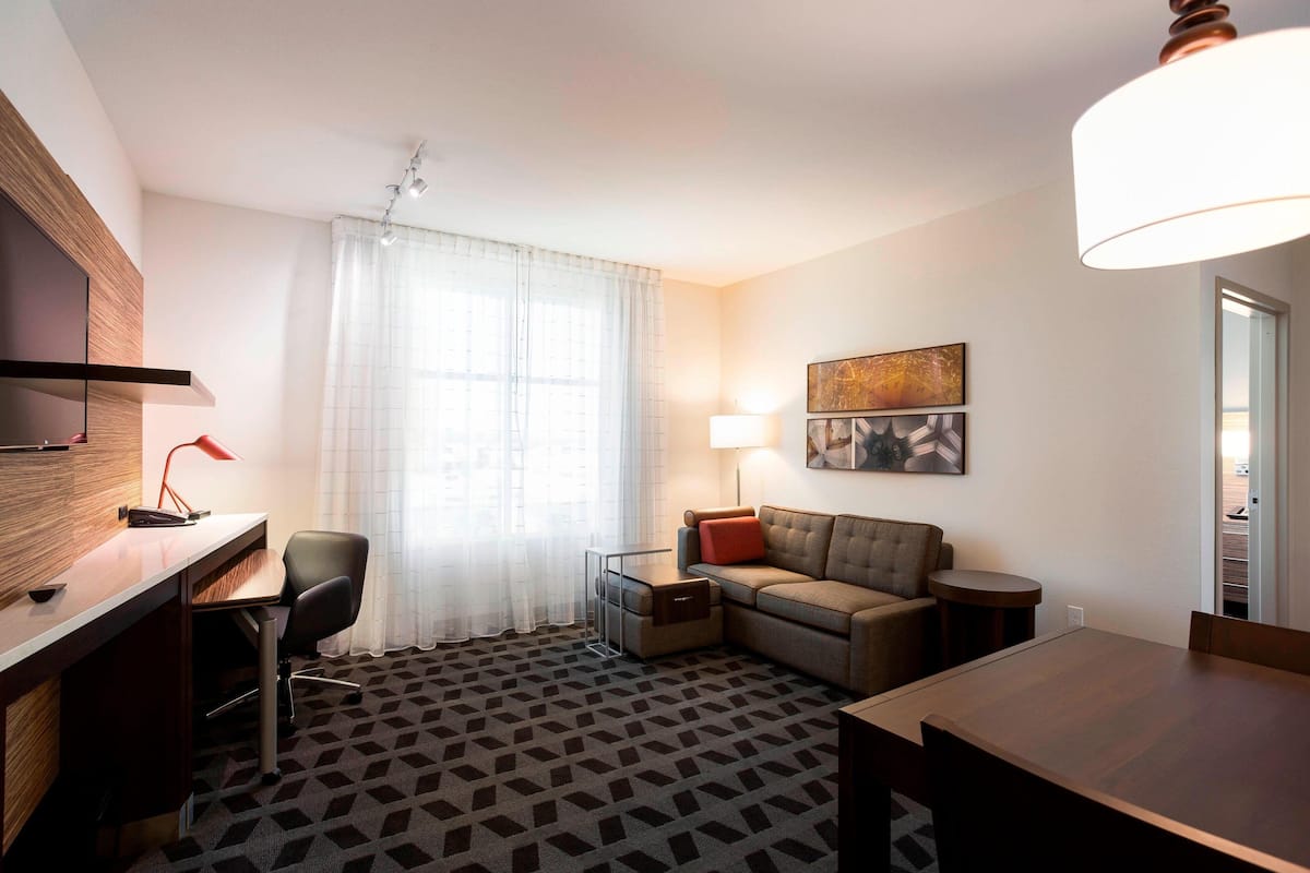 Een moderne hotelkamer met een houten bureau, een comfortabele bank, een klein tafeltje en een televisie.
