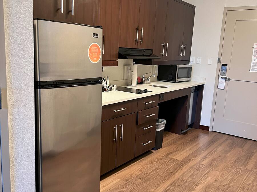 A modern kitchen with stainless steel appliances, wooden cabinets, and a microwave.