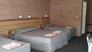 A room with two beds, a wooden headboard, and a brick wall. - Aaron Inn Motel (Narrabri)