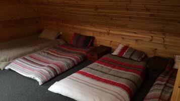 Una camera in stile chalet con due letti, ognuno con biancheria a righe, una testiera in legno e un comodino in legno.