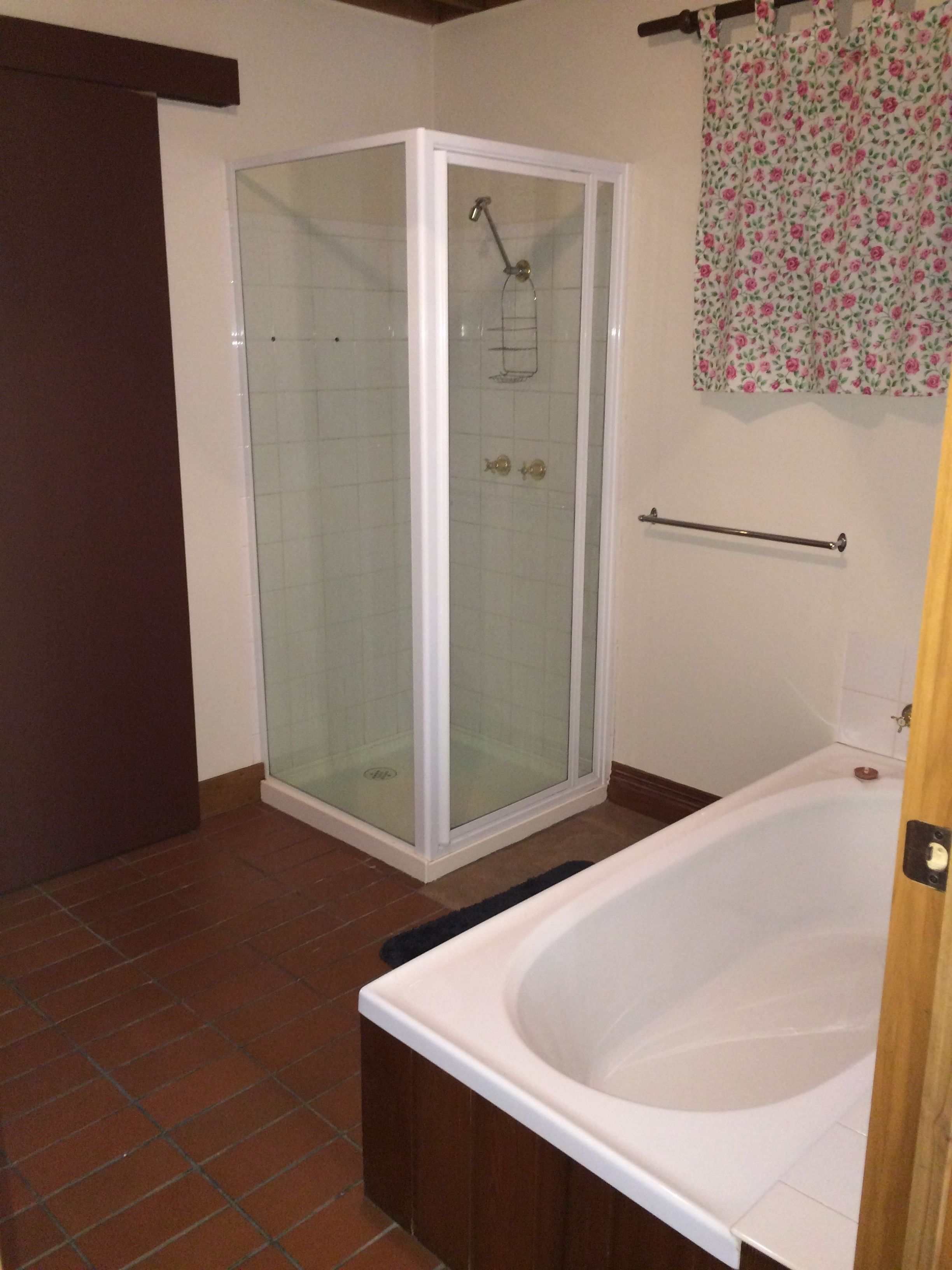 Ein Badezimmer mit einer Duschkabine, einer weißen Badewanne und einem blumigen Vorhang.