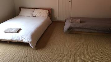 A bedroom with two beds, a door, and a carpeted floor.
