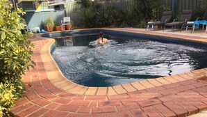 A swimming pool with a brick border, surrounded by pebbles and plants. - Sunrise Motel (Barooga)