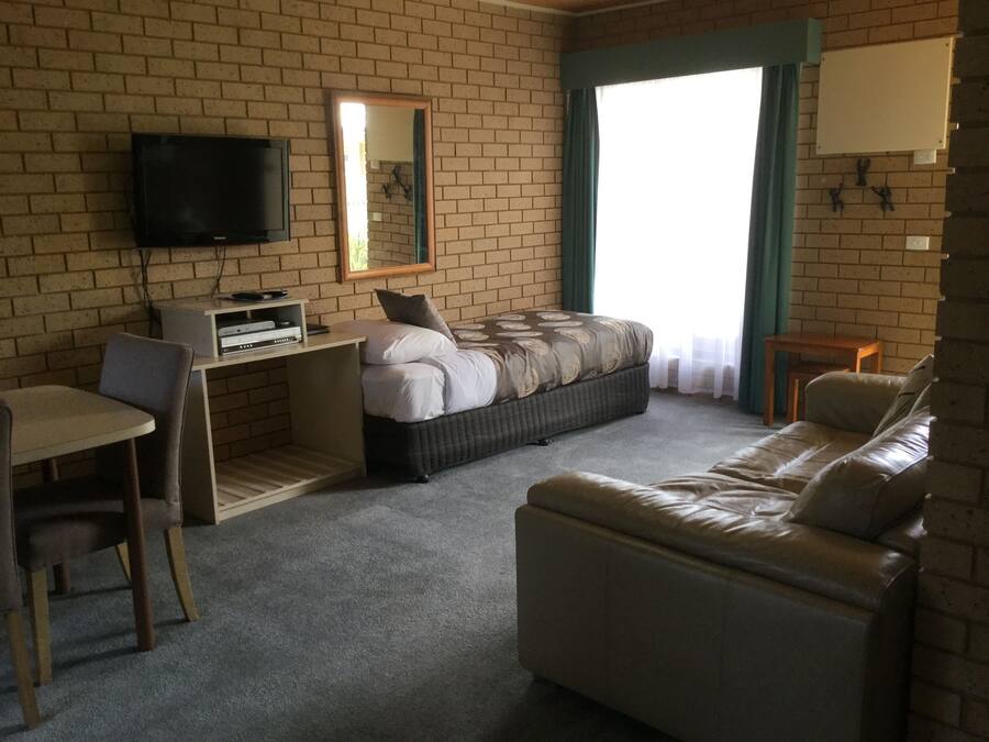 Ein Zimmer mit einem Bett, einem Schreibtisch, einem Fernseher und einem Sofa.
