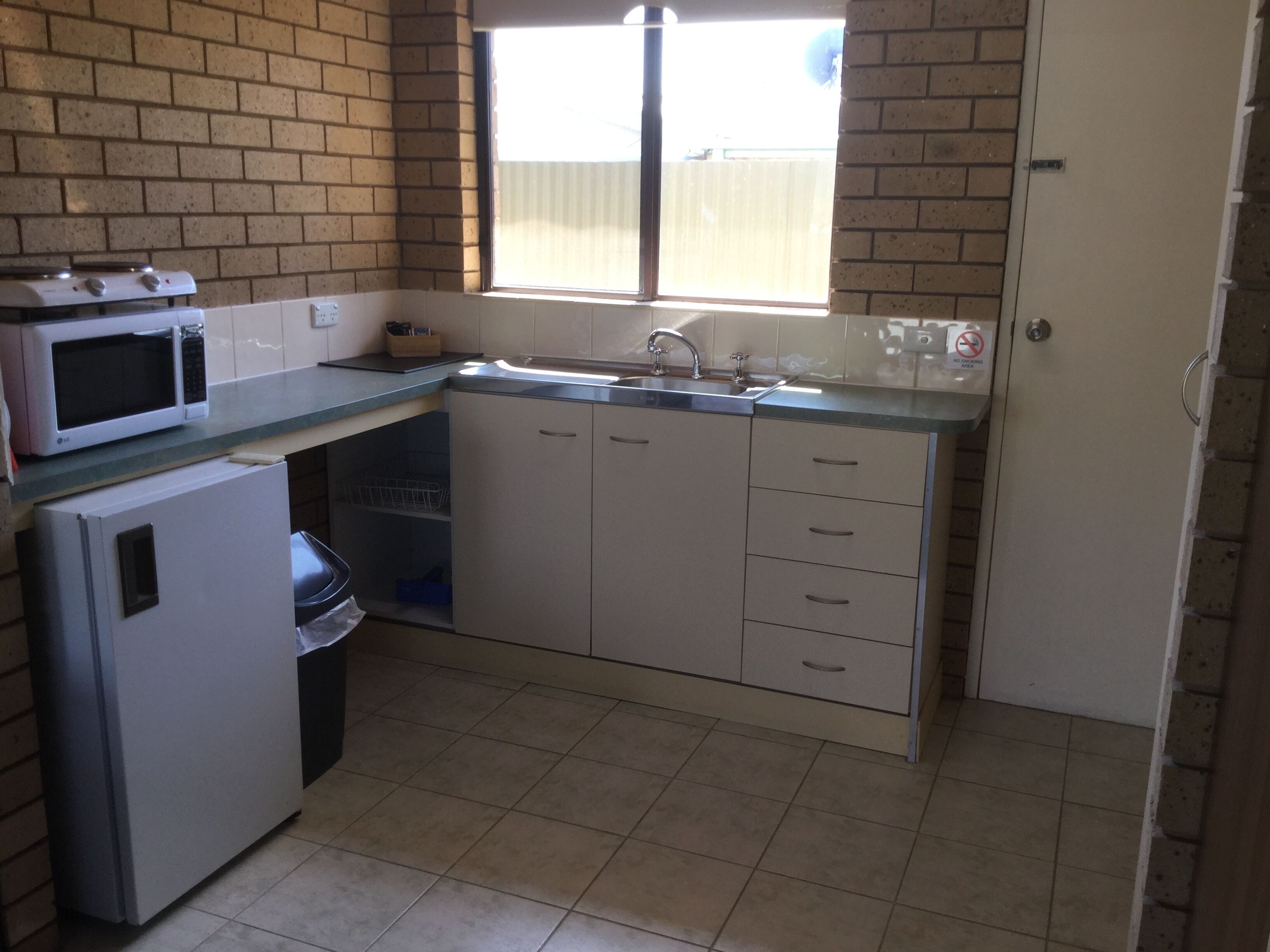 Cocina compacta con microondas, refrigerador, pileta y placares.