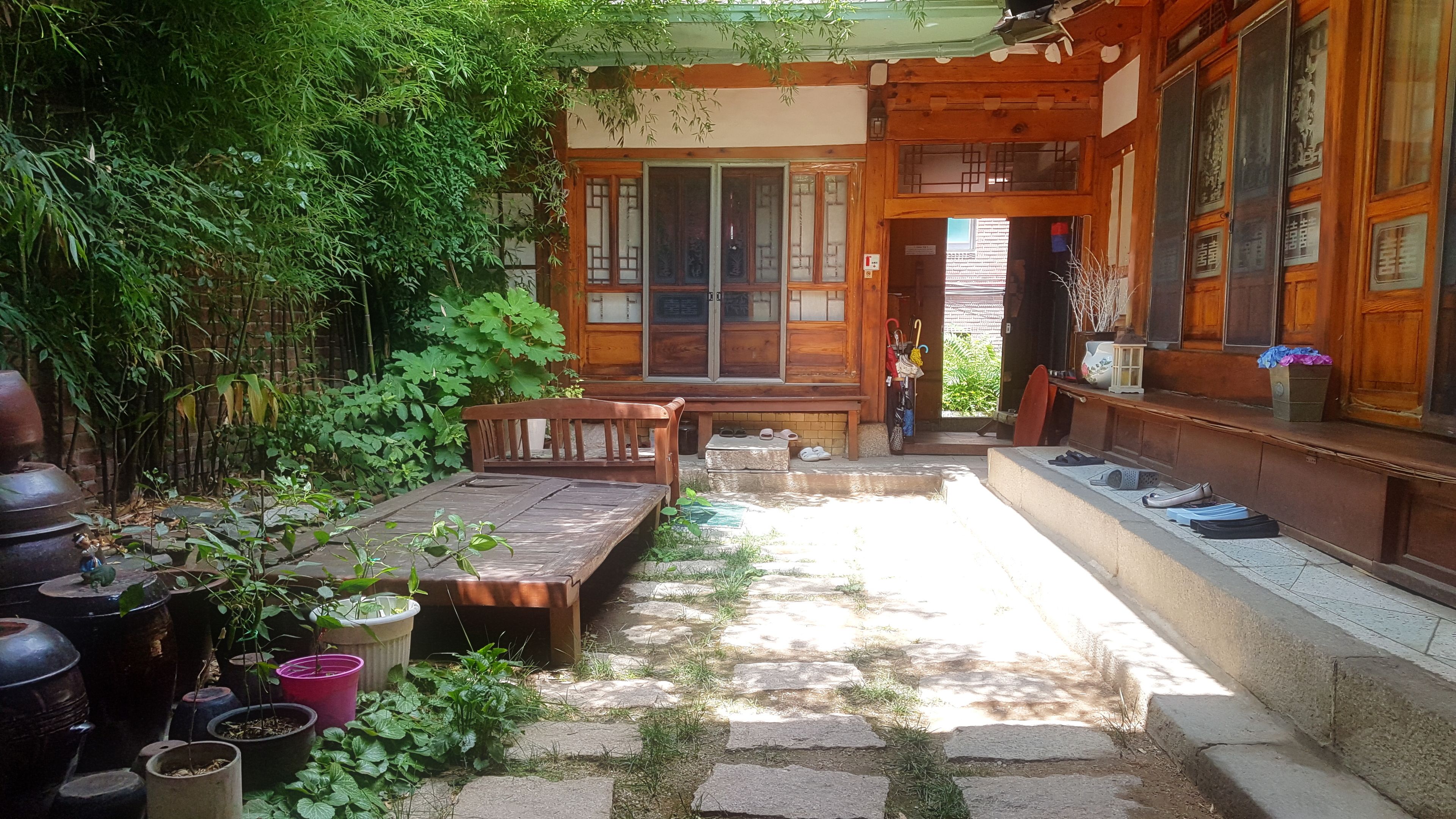 A traditional wooden building with a stone pathway leading to a wooden bench and a small table.