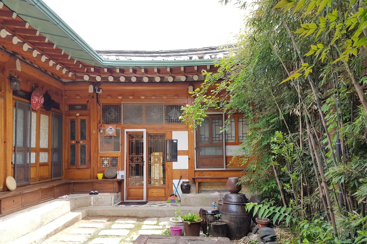 A traditional wooden building with a tiled roof, a wooden door with a lattice design, and a stone-paved courtyard.