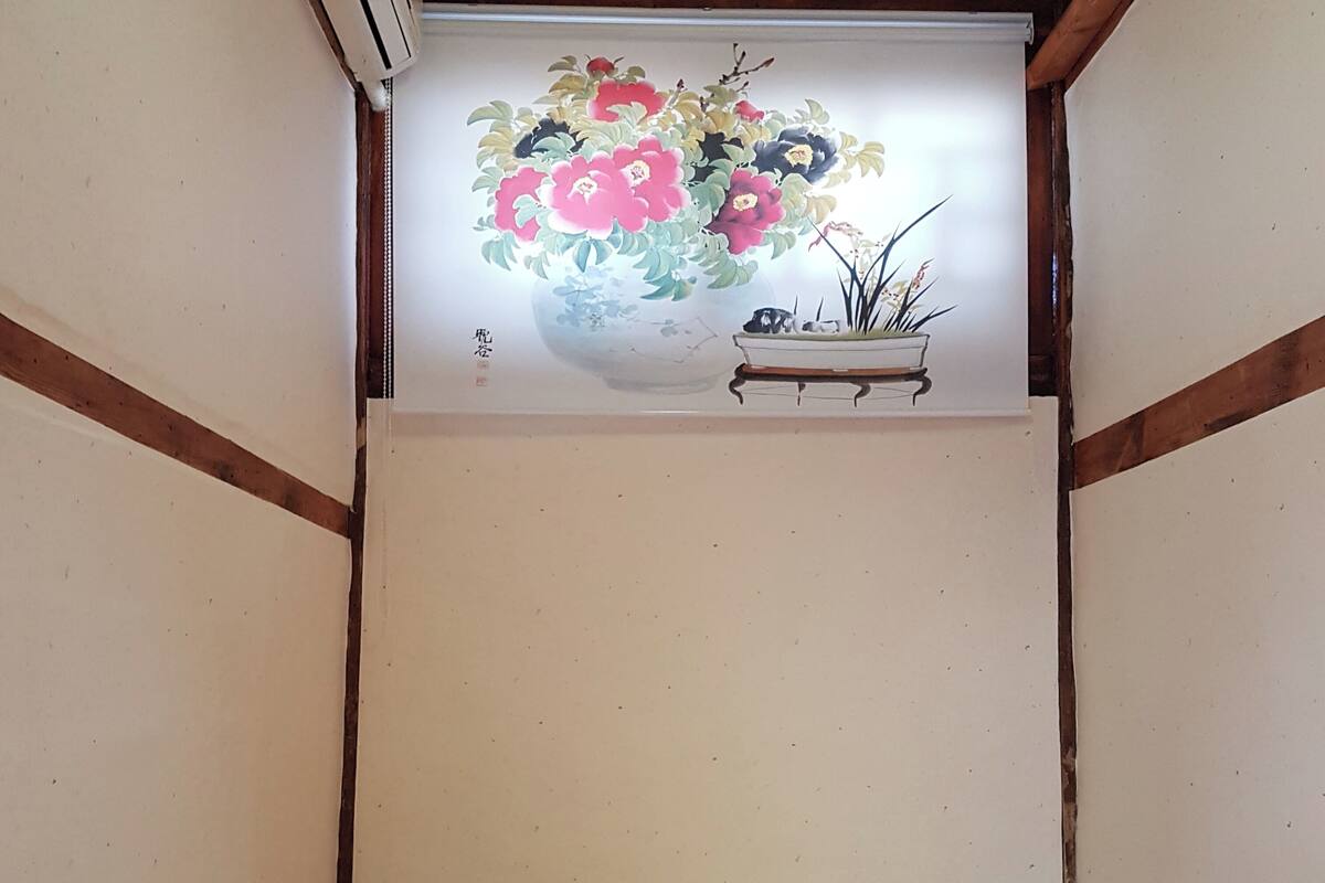 A room with a ceiling painted in a light color, a wooden beam structure, and a floral mural on the wall.