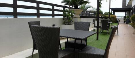 An outdoor patio area with wicker furniture and a view of the sea.