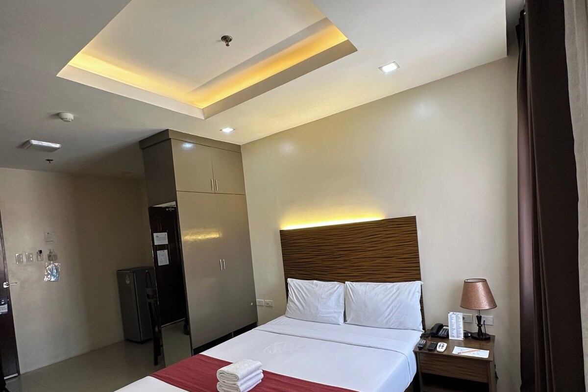 Une chambre d’hôtel avec un grand lit, une table de chevet, un bureau et une armoire.