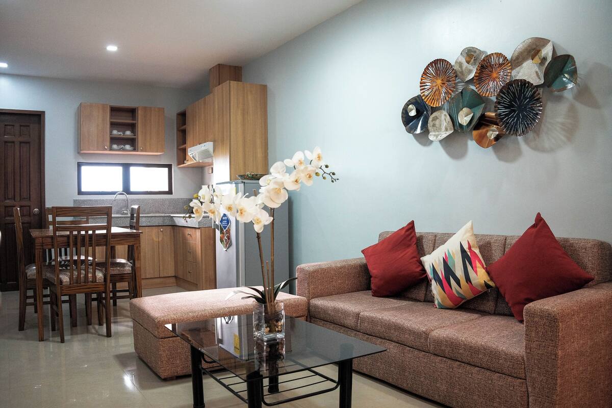 A modern living room with a sofa, coffee table, and a dining area with chairs and a table.