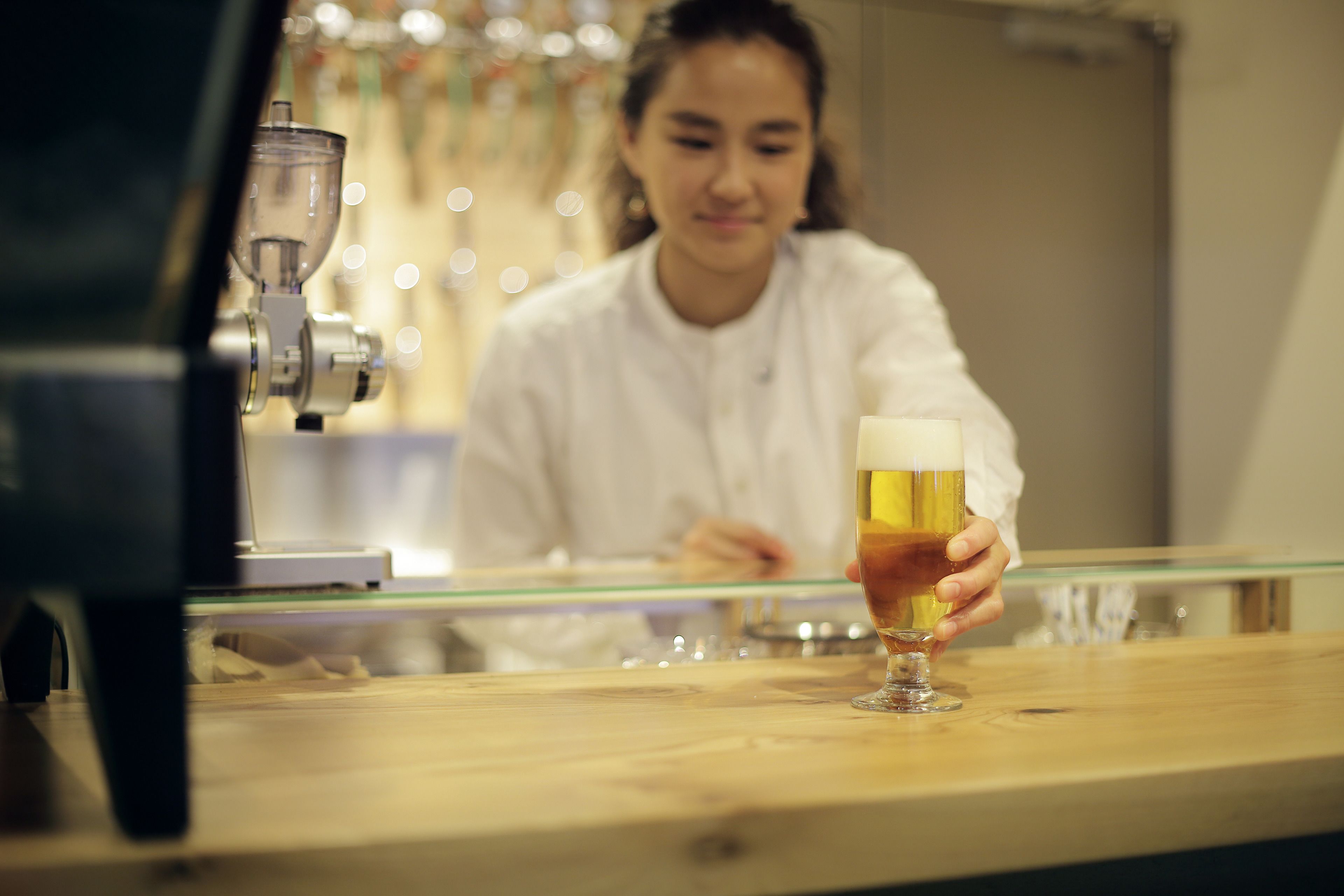 Una persona sosteniendo una cerveza en la barra de un bar, con una grifo de cerveza al fondo.