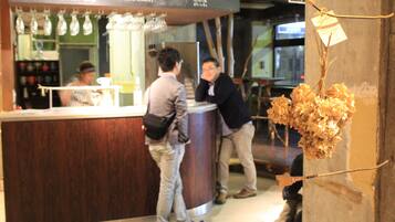 A bar area with a counter, hanging lights, and a menu board.