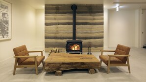 A room with a wood-burning stove, two wooden chairs, and a large wooden table. - HOTEL NUPKA (Obihiro)
