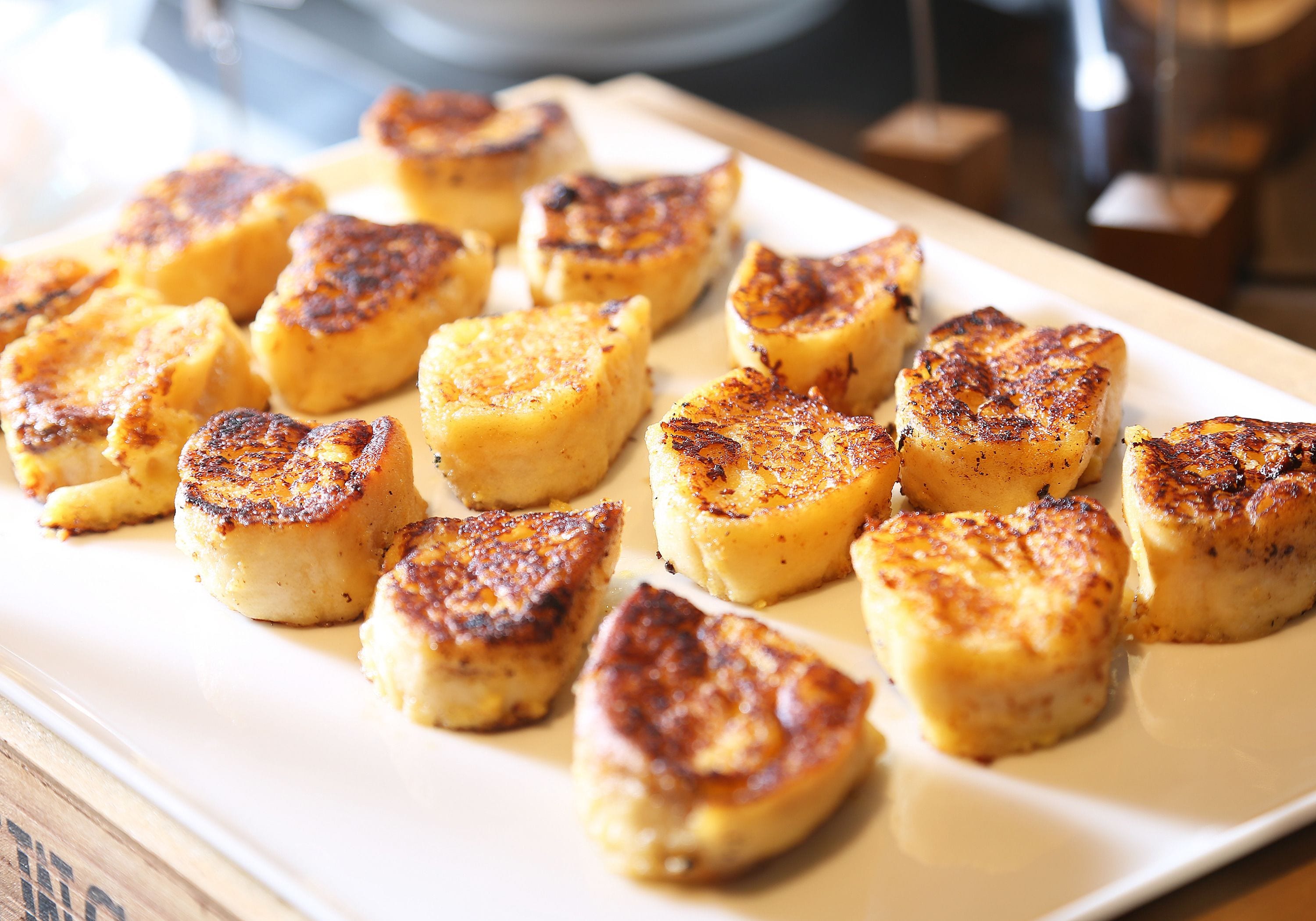 A plate of grilled scallops arranged on a white rectangular plate.