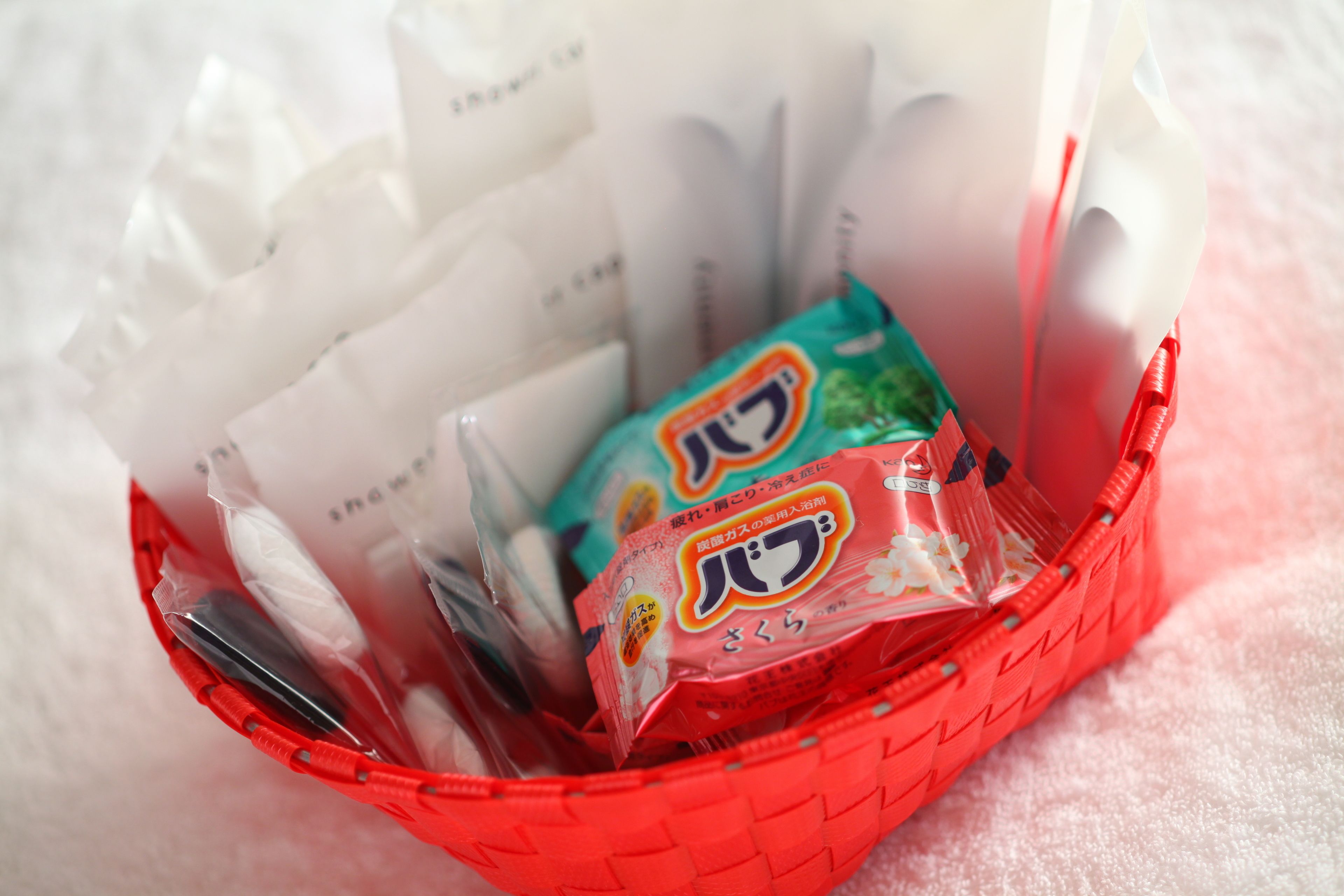 A red basket containing various packaged items, including a green and red package with Japanese text.
