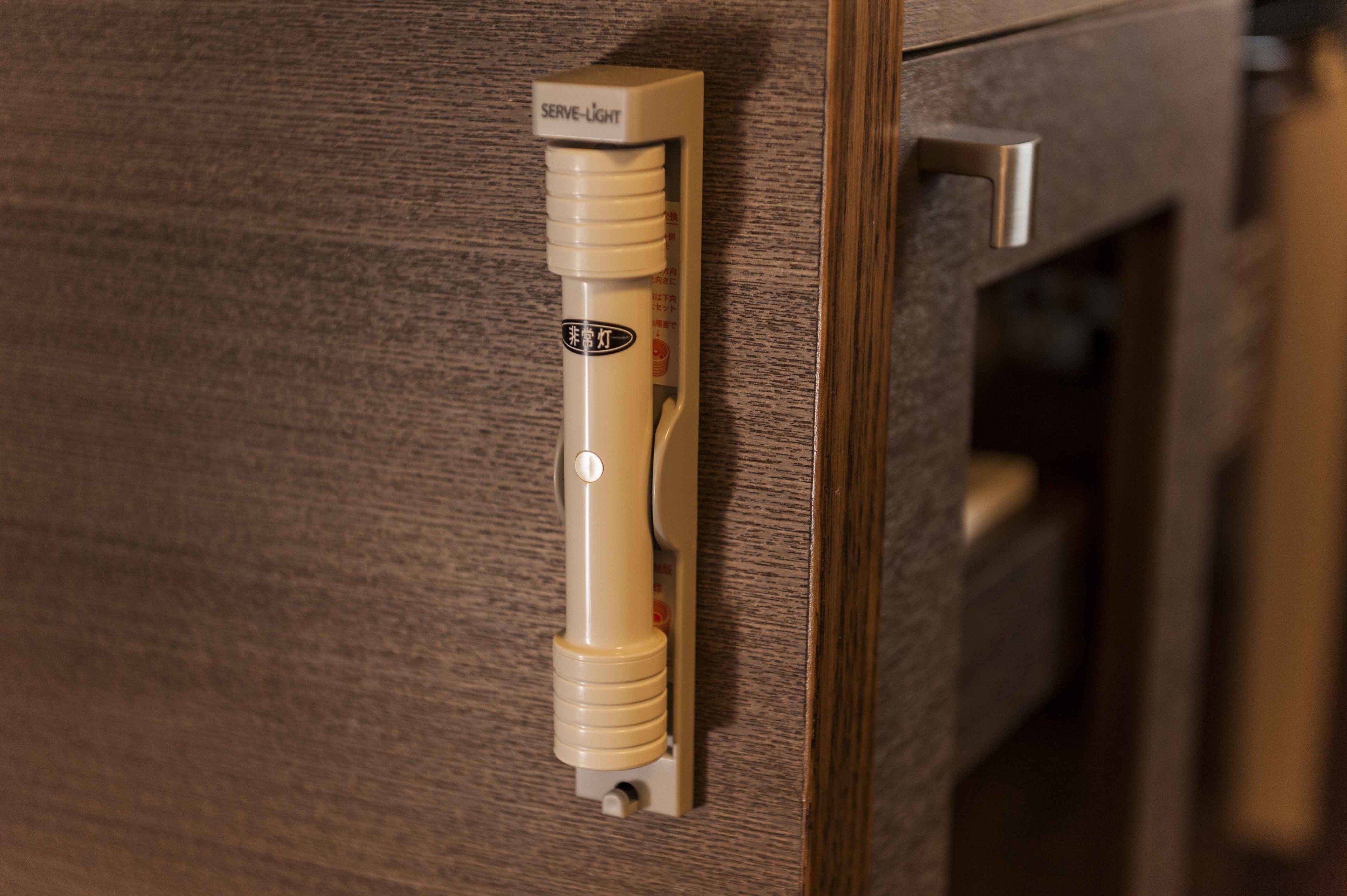 Une poignée de porte avec une étiquette indiquant « lumière pour signaler la présence » et un bouton.