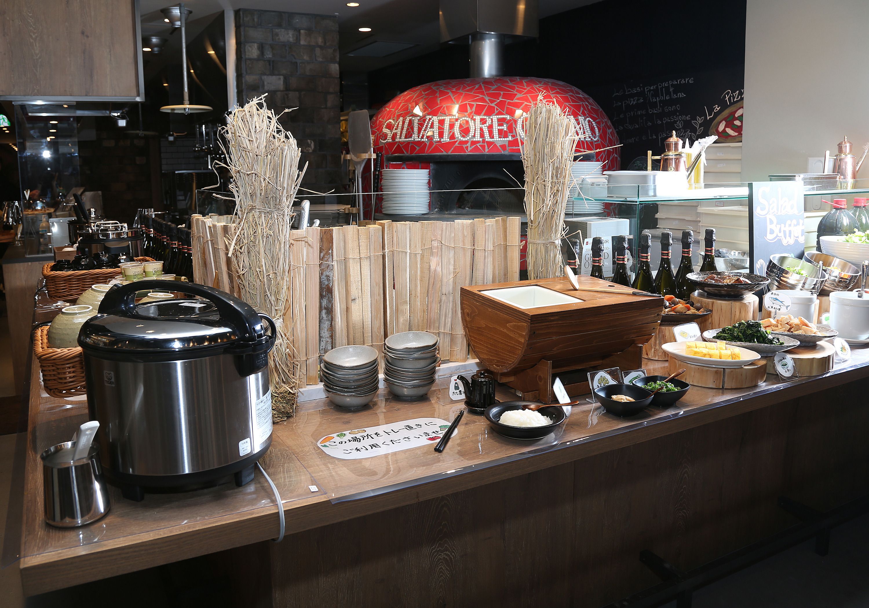 A restaurant counter with a pizza oven, various dishes, and condiments.
