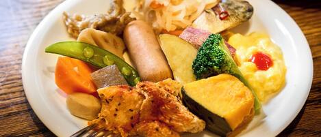 A plate of assorted food including vegetables, a piece of fish, and a small sausage.