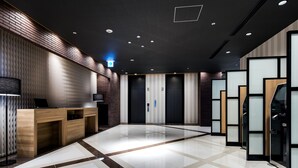 A modern lobby with a reception desk, elevators, and a polished floor.