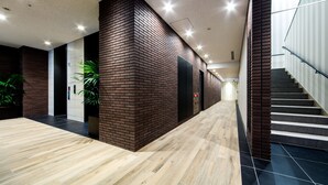 A modern interior with a wooden floor, brick walls, and a staircase with glass railings.