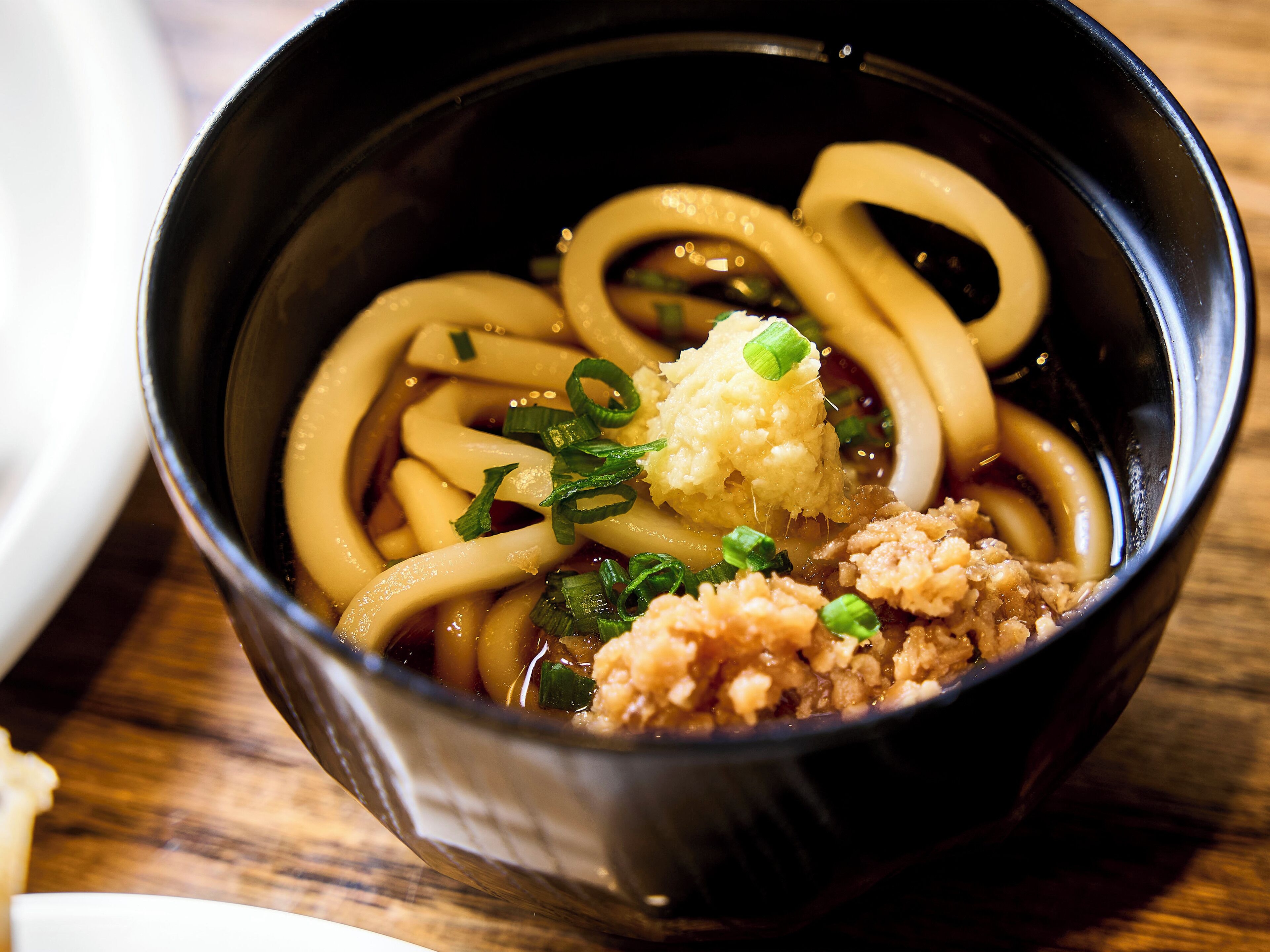 Un tazón de ramen con fideos, un ingrediente y caldo.