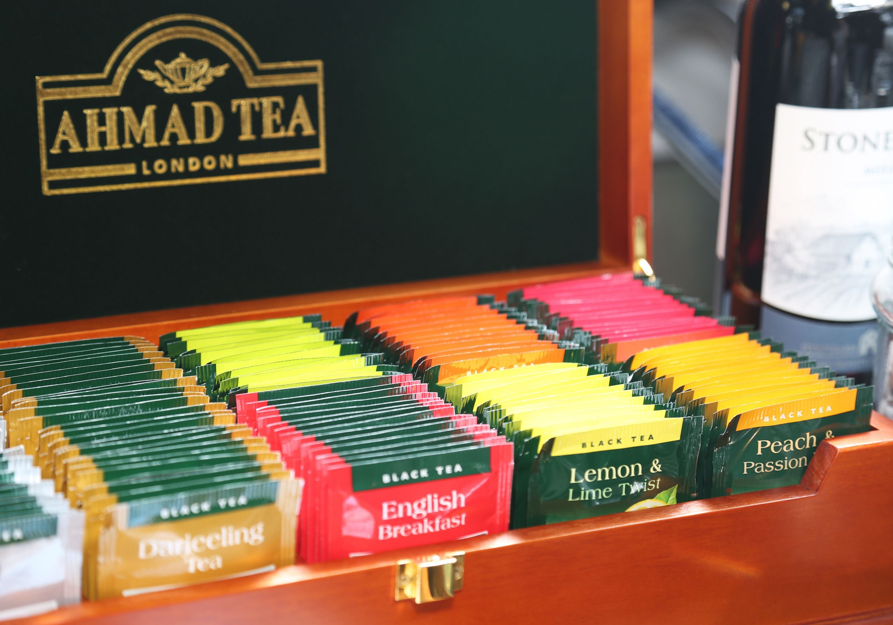 Une sélection de sachets de thé de différentes couleurs, comprenant des variétés comme le Darjeeling, l’English Breakfast, le thé au citron et au citron vert, le thé noir et le thé à la pêche et aux fruits de la passion.