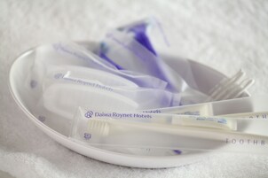 Un tazón con productos de higiene bucal, incluyendo cepillos de dientes y pasta dental, con la marca visible.