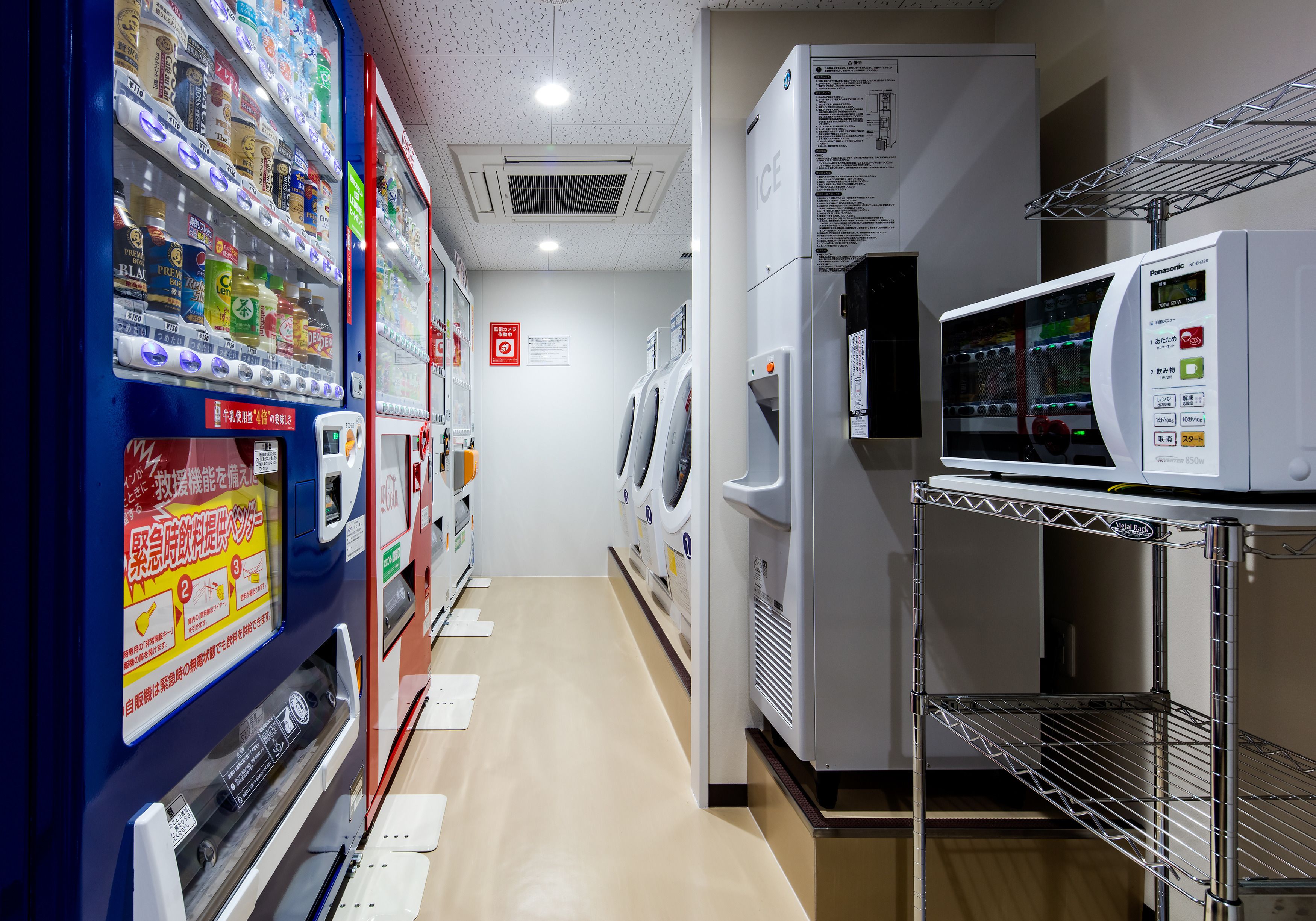 A hotel corridor with vending machines, a microwave, and a refrigerator.