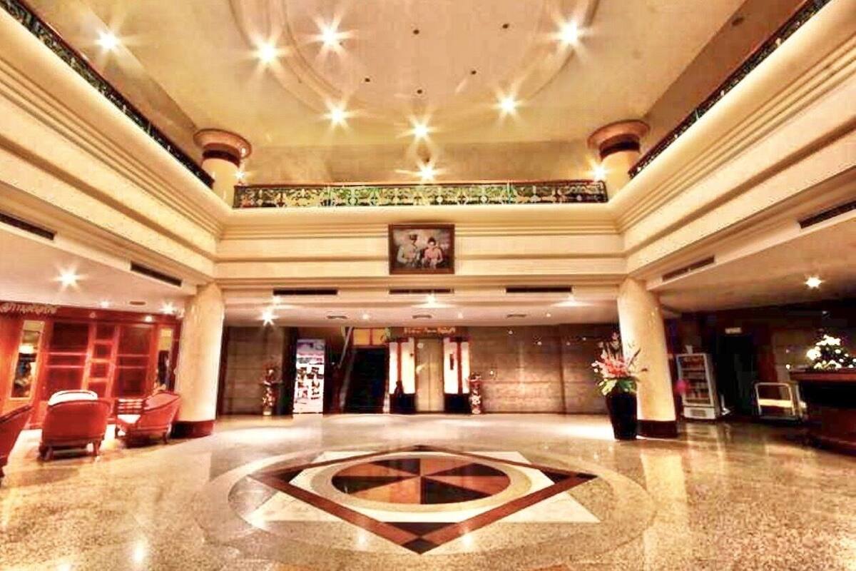 A spacious lobby with a central geometric floor design, a reception desk, and a framed picture above it.