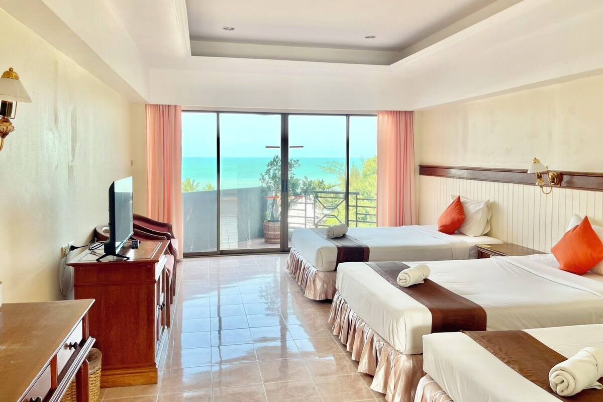 A hotel room with a balcony, a TV, a desk, and two beds.