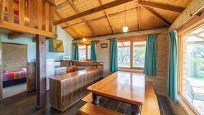 Eine rustikale Küche mit Holzbalken, einem großen Esstisch aus Holz und einer Steinwand.