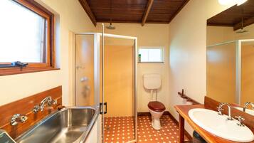 A bathroom with a wooden vanity, a sink, a toilet, and a shower with a glass door.