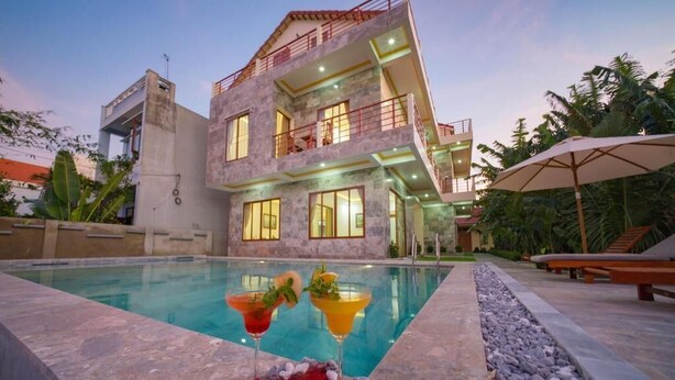 A modern two-story building with a swimming pool, outdoor seating, and a well-maintained garden. - Herbal Tea Homestay (Da Nang)