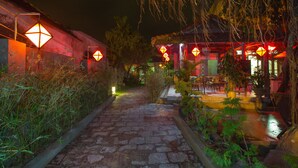 A stone pathway leading to a building with traditional lanterns and outdoor seating. - Herbal Tea Homestay (Da Nang)