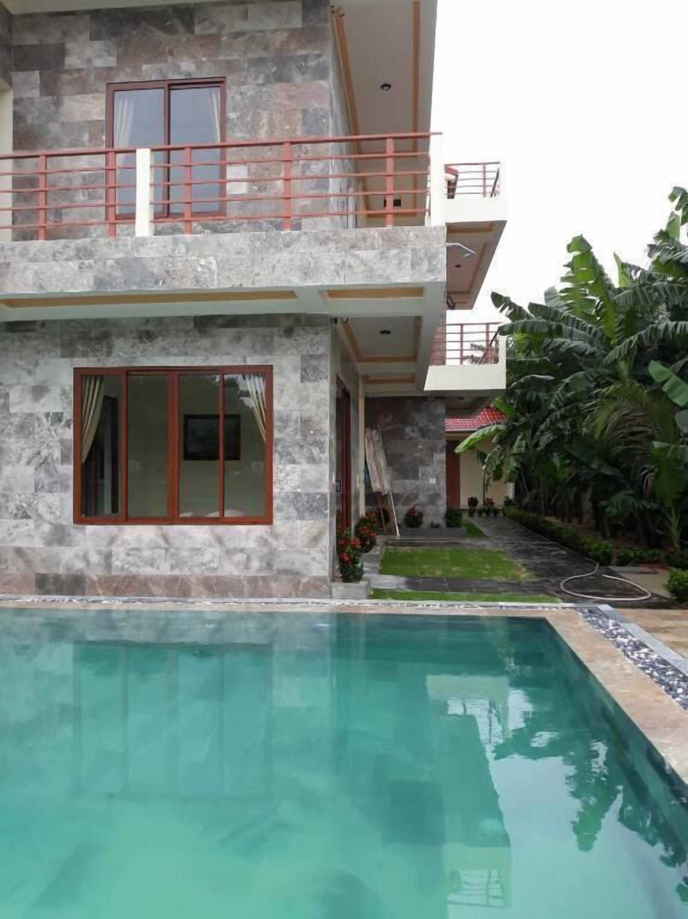 A two-story house with a swimming pool in front.